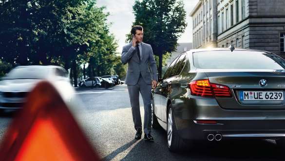 BMW Mobile Care BMW Mobile Care mann i telefon foran en BMW