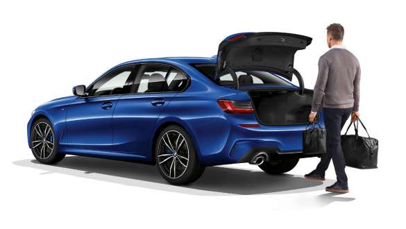 BMW 3-serie Sedan med automatisk baklukebetjening. BMW 3-serie Sedan med fører som åpner bakluken med den automatiske baklukebetjeningen sett skrått bakfra.