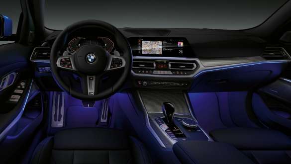 BMW 3-serie Sedan med bakgrunnsbelysning. Førerplassen i BMW 3-serie Sedan med fotrommet belyst av blå bakgrunnsbelysning sett forfra.