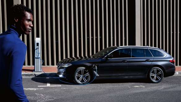 Plug-in hybrid BMW 5-serie Touring 2021 G31 LCI, sett fra siden under lading Plug-in hybrid BMW 5-serie Touring 2021 G31 LCI, sett fra siden under lading med modell