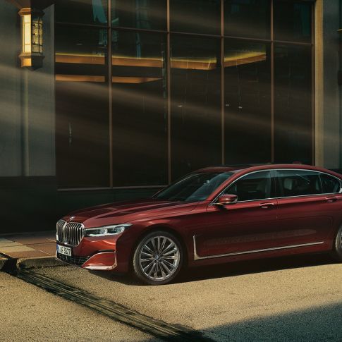 BMW Individual 7-serie Sedan sett fra siden Rød BMW Individual 7-serie Sedan sett fra siden foran bylandskap