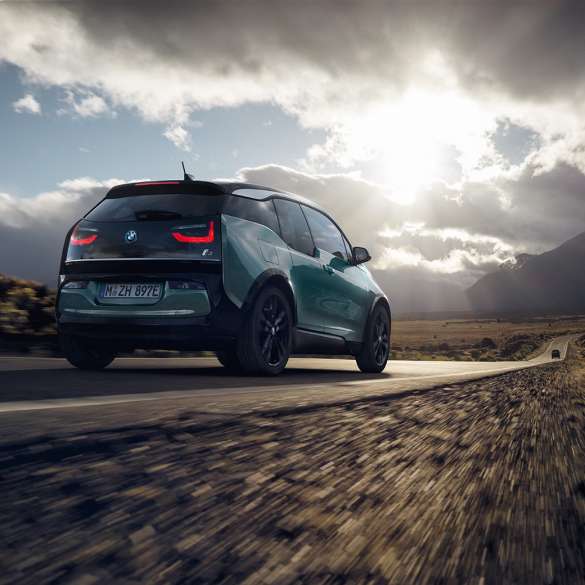 BMW i3 2018 sett skrått bakfra kjørende på landevei BMW i3 I01 2018 Jucarobeige med detaljer i frostgrå metallic sett skrått bakfra kjørende på landevei