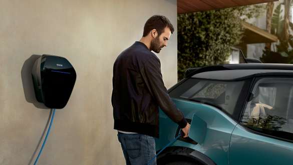 BMW i3 2018 ved en offentlig ladestasjon Jucarobeige med detaljer i frostgrå metallic Et par lader sin BMW i3 ved en offentlig ladestasjon I01 2018 Jucarobeige med detaljer i frostgrå metallic