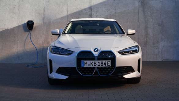 Sett forfra med BMW Wallbox BMW i4 eDrive40 G26 2021 BMW i4 eDrive40 G26 2021 Mineralhvit Sett forfra foran husvegg med BMW Wallbox ladestasjon
