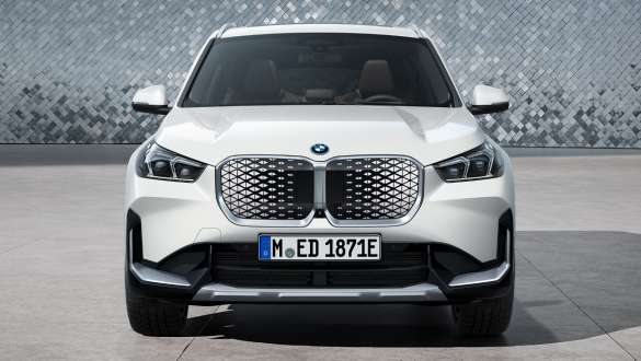 BMW iX1 U11 BEV Sett forfra discokulevegg BMW iX1 U11 BEV 2022 Mineralhvit metallic sett forfra parkert foran discokulevegg