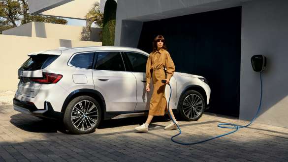 BMW iX1 U11 BEV 2022 Garasjeinnkjørsel BMW iX1 U11 BEV 2022 Mineralhvit metallic sett skrått fra siden parkert i garasjeinnkjørselen