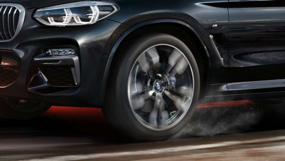 BMW X3 M40i og BMW X3 M40d sett fra siden. Utvendig design på BMW X3 M40i og BMW X3 M40d i safirsort metallic som kjører, sett fra siden med roterende lettmetallfelg.