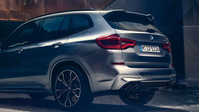 BMW X3 M Competition sett fra siden bak. Utvendig design på BMW X3 M Competition i doningtongrå metallic med to personer i forgrunnen sett fra siden bak.