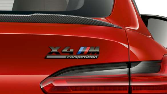 Hekken på BMW X4 M Competition med X4 M Competition-signatur. Utvendig design på BMW X4 M Competition i torontorød metallic, nærbilde av hekk med hekkspoiler i karbonfiber og X4 M Competition-signatur.