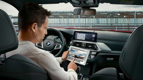BMW Connected. BMW X4 M-modeller med BMW Connected og kvinne med lysende globus i hånden.