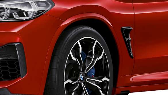 BMW X4 M Competition, nærbilde av hekken sett fra siden. Utvendig design på BMW X4 M Competition i torontorød metallic, nærbilde av hekk med spesielt M understell sett fra siden.