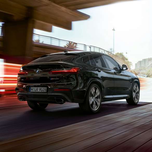 BMW X4 M40i, sett skrått forfra. Utvendig design på BMW X4 M40i i safirsort metallic som kjører, sett skrått forfra med lysstriper.