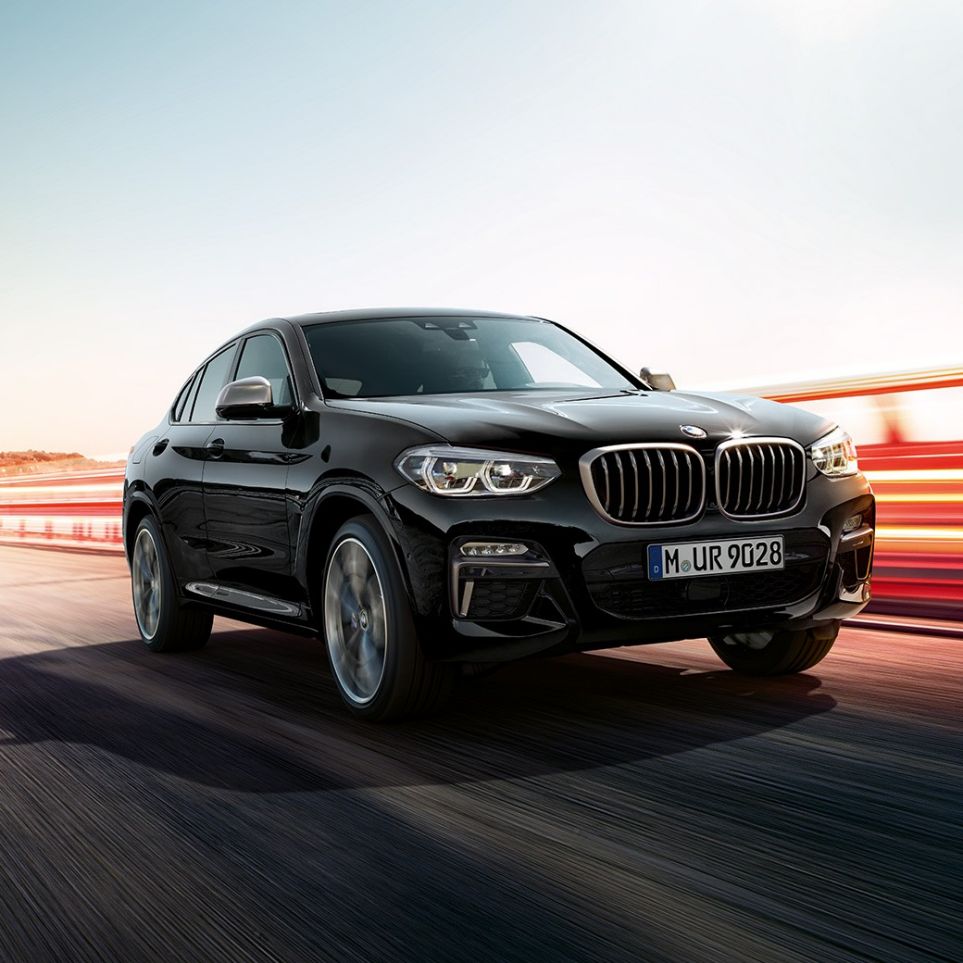 BMW X4 M40i og BMW X4 M40d sett skrått forfra. Utvendig design på BMW X4 M40i og BMW X4 M40d i safirsort metallic sett skrått fra venstre foran med lysstriper.