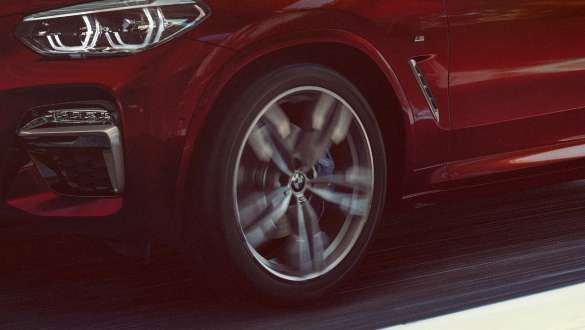 Adaptivt M understell BMW X4 Adaptivt M understell BMW X4 M40i G02 2018 Flamencorød med briljanteffekt sett skrått fra siden med aluminiumsfelger