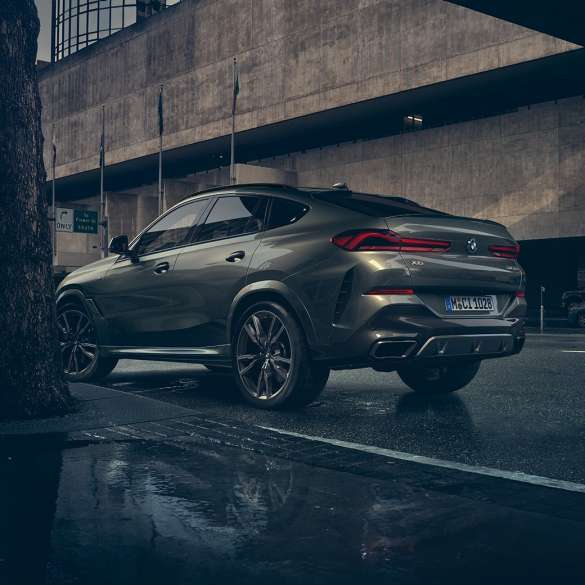 BMW X6 eksteriør. BMW X6 i hekkperspektiv foran bylandskap.