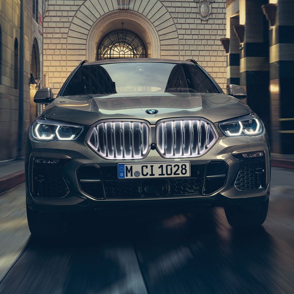 BMW X6 med BMW-grill ‘Iconic Glow’. BMW X6 sett forfra foran bylandskap.