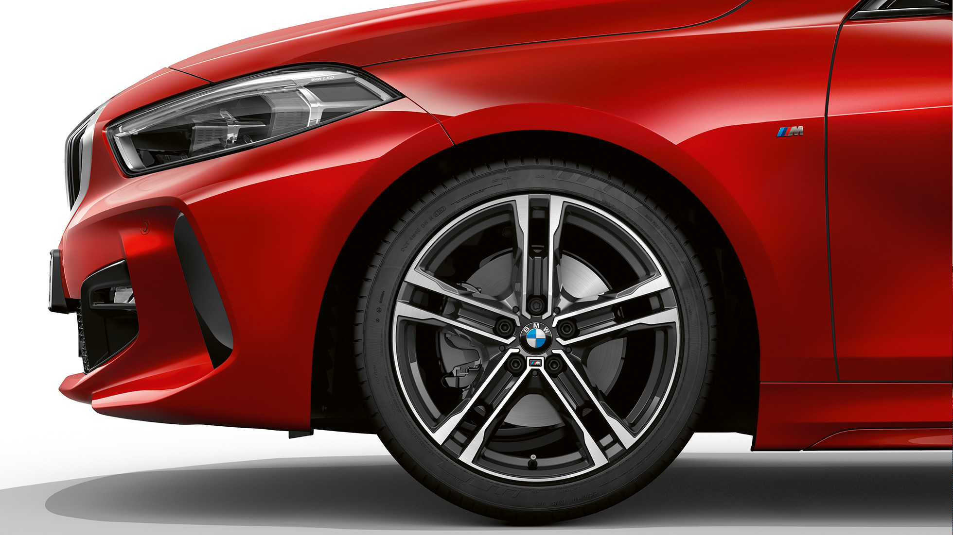 BMW 1-serie Modell M Sport, sideveis forfra. BMW 1-serie Modell M Sport i Melbourne Rot metallic, sideveis forfra med 17" M lettmetallfelger Dobbelteke 550 M tofarget.
