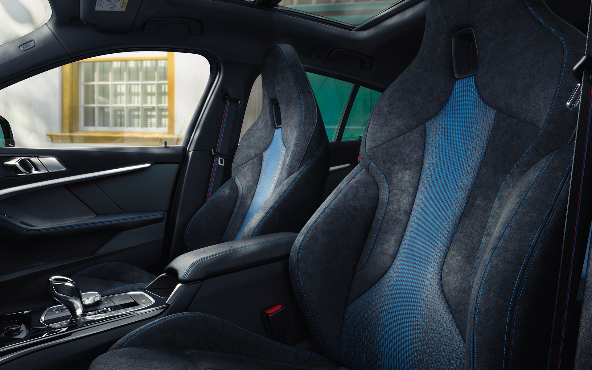 Ergonomisk formet M sportsseter i BMW 1-serie F40 med blå kontrastsøm og integrert hodestøtte.