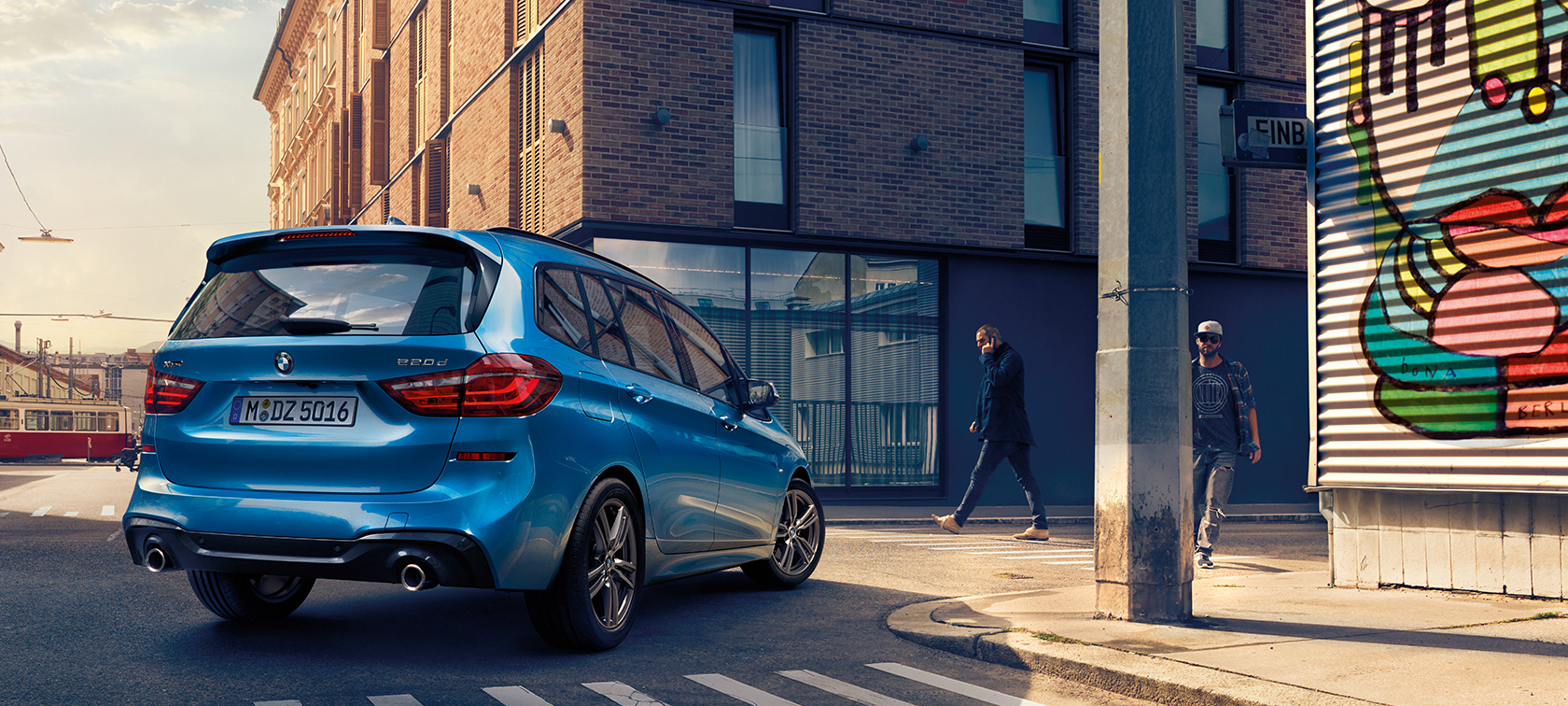 BMW 2-serie Gran Tourer sett ovenfra Mann ved siden av BMW 2-serie Gran Tourer F46 Facelift 2018 Estoril blå metallic Sett ovenfra parkerende på veien