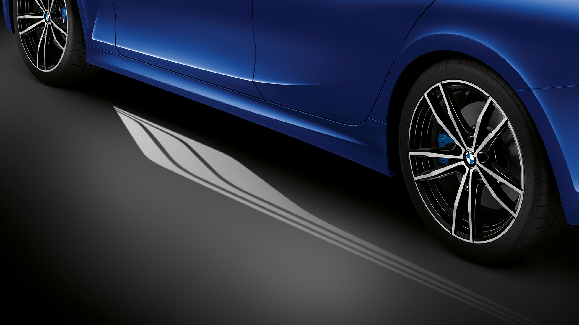 BMW 3-serie sedan, Welcome Light Carpet. Nærbilde av åpen førerdør med Welcome Light Carpet sett fra siden.