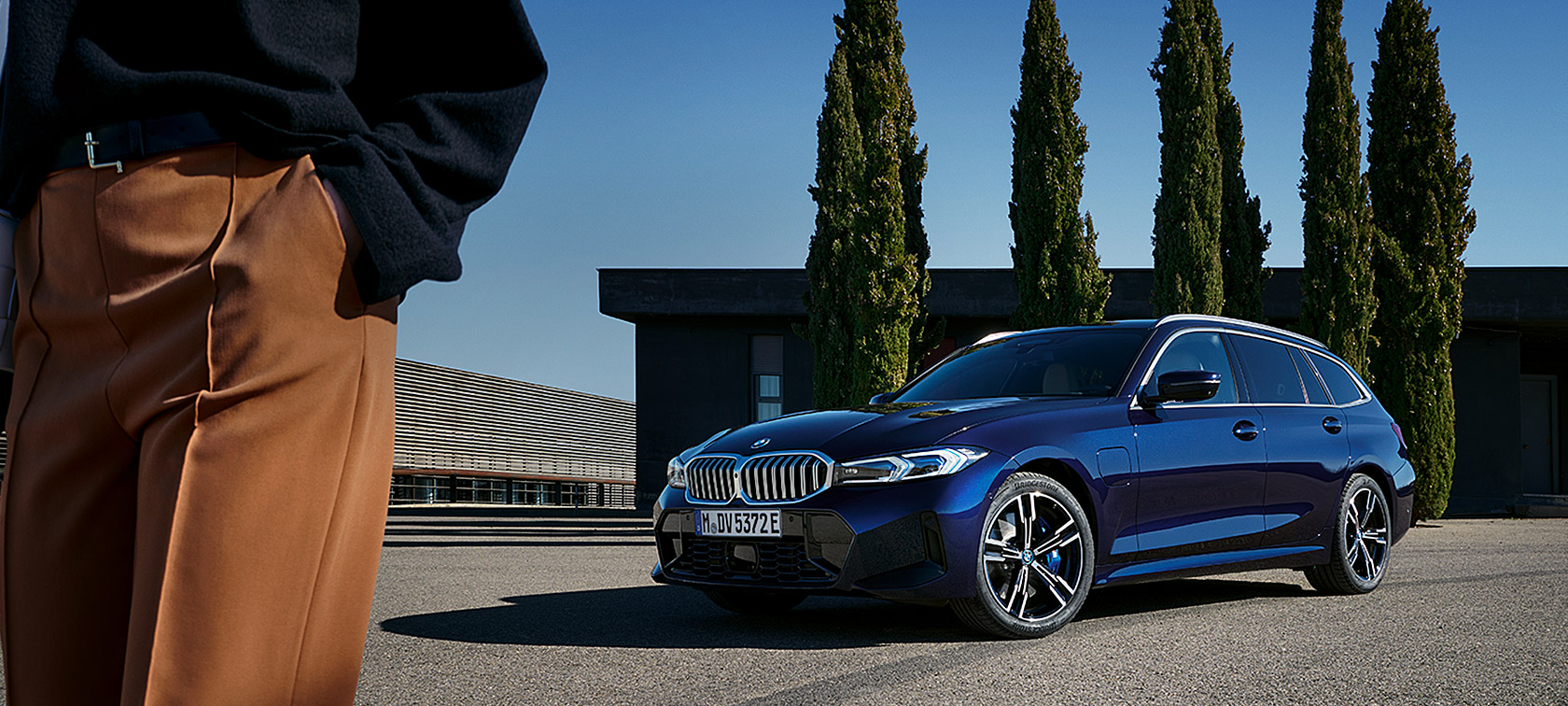 BMW 3-serie Touring LCI G21 Tanzanite Blue II sett skrått forfra stående foran trær