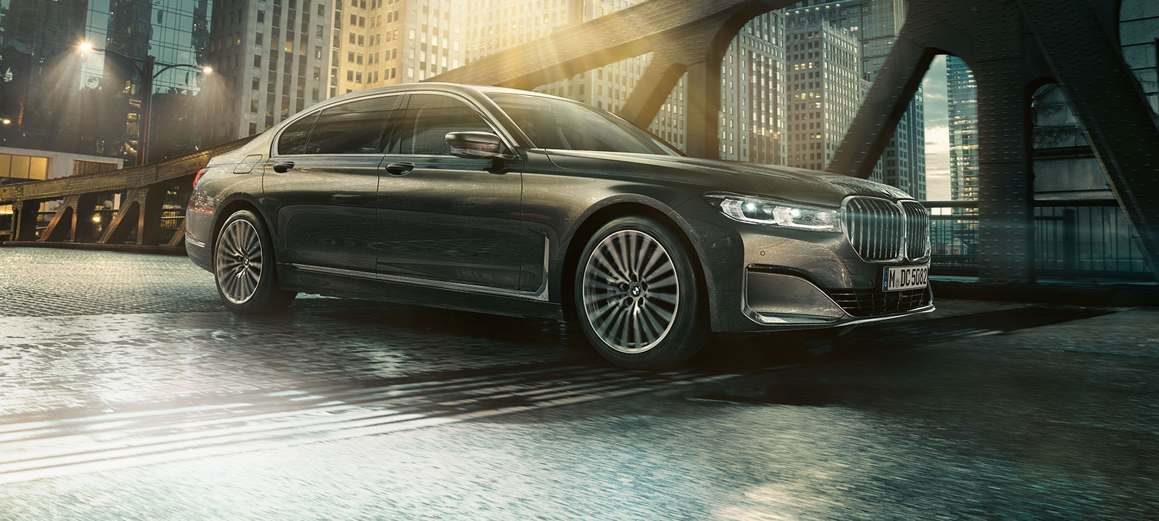 BMW 7-serie Sedan sett fra siden BMW 7-serie Sedan som står med åpen dør foran belyst hotell, sett fra siden