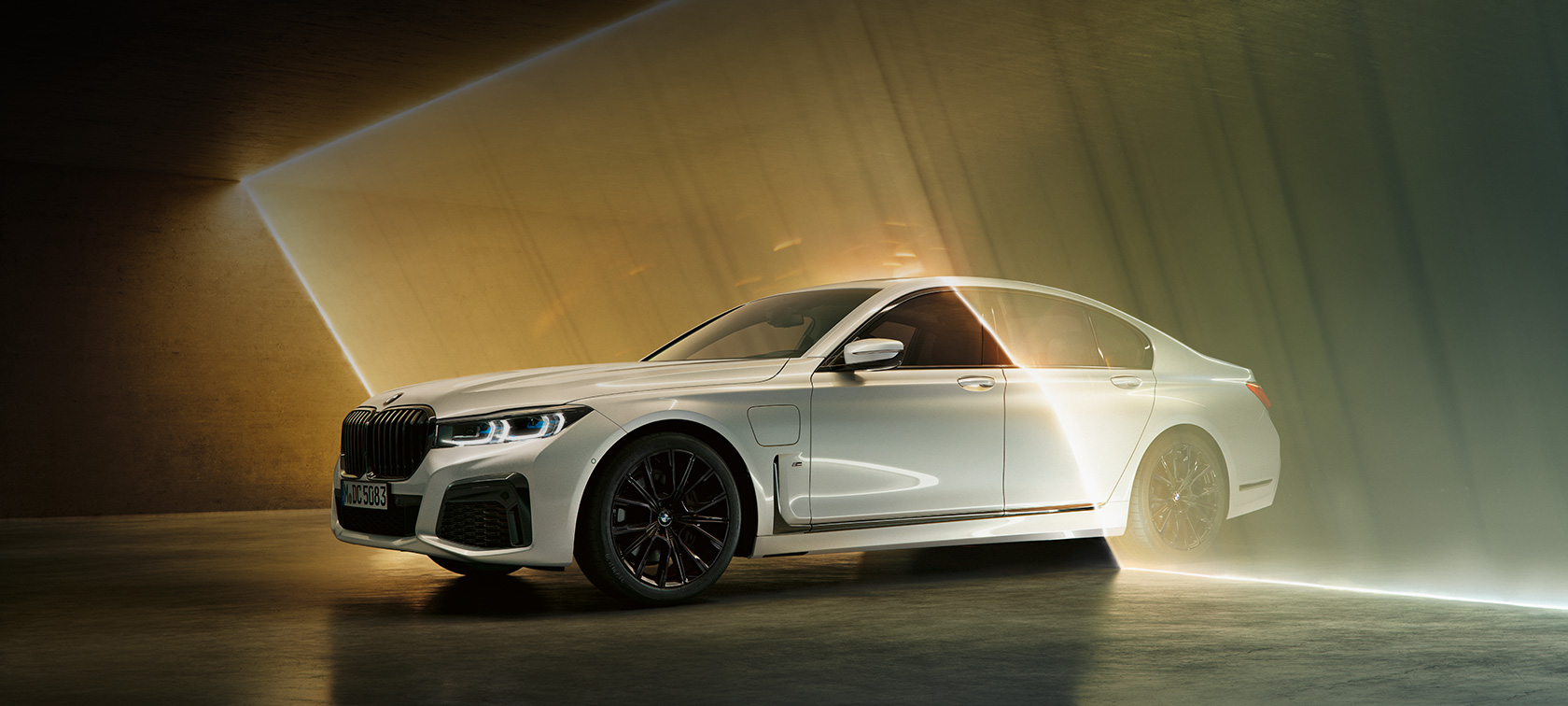 Hvit BMW 7-serie Sedan sett skrått forfra BMW 7-serie Sedan: Hvit BMW omgitt av lysstråle sett skrått forfra