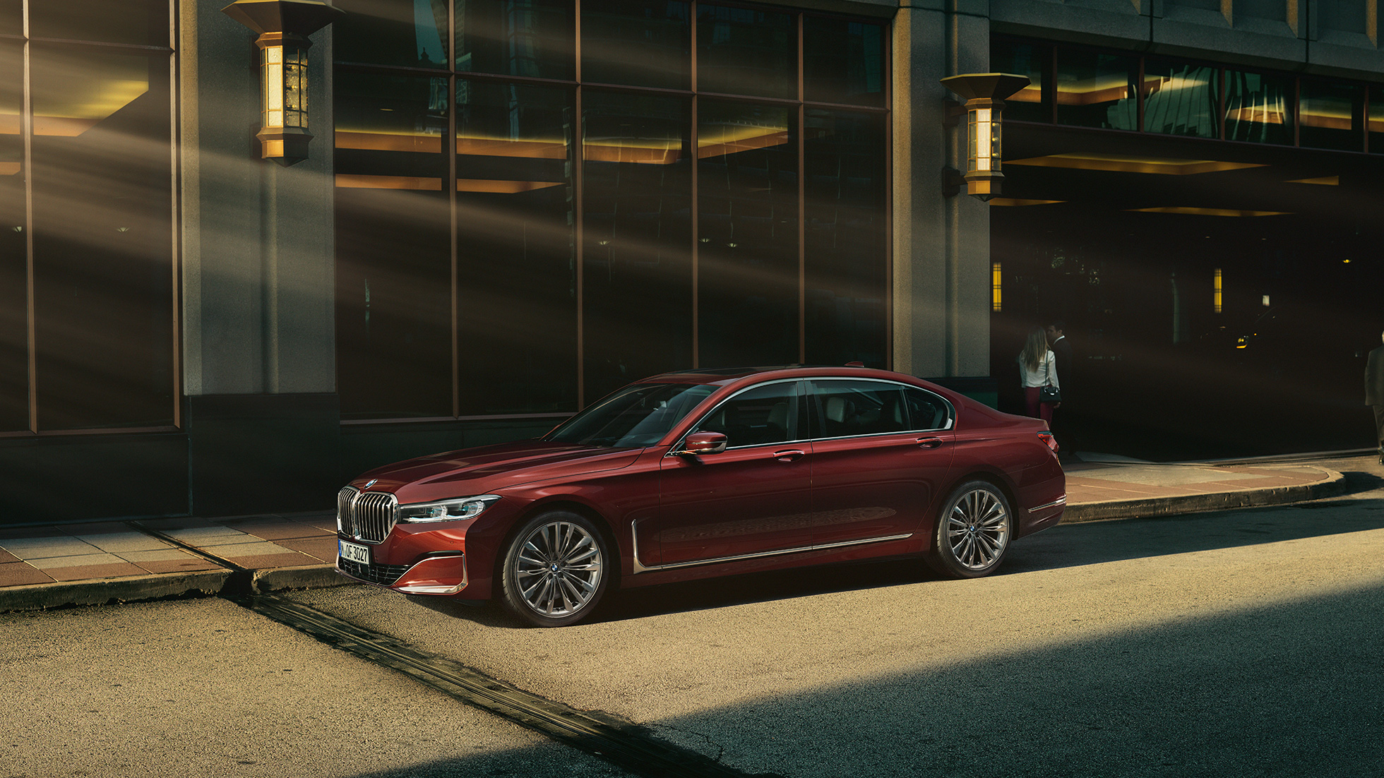 BMW Individual 7-serie Sedan sett fra siden Rød BMW Individual 7-serie Sedan sett fra siden foran bylandskap