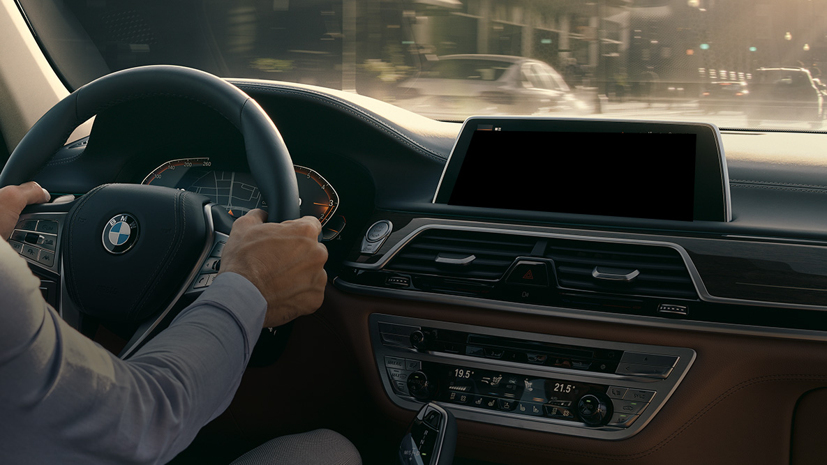 BMW Intelligent Personal Assitant BMW Intelligent Personal Assitant: Mann kjører en BMW, nærbilde av Live Cockpit Professional