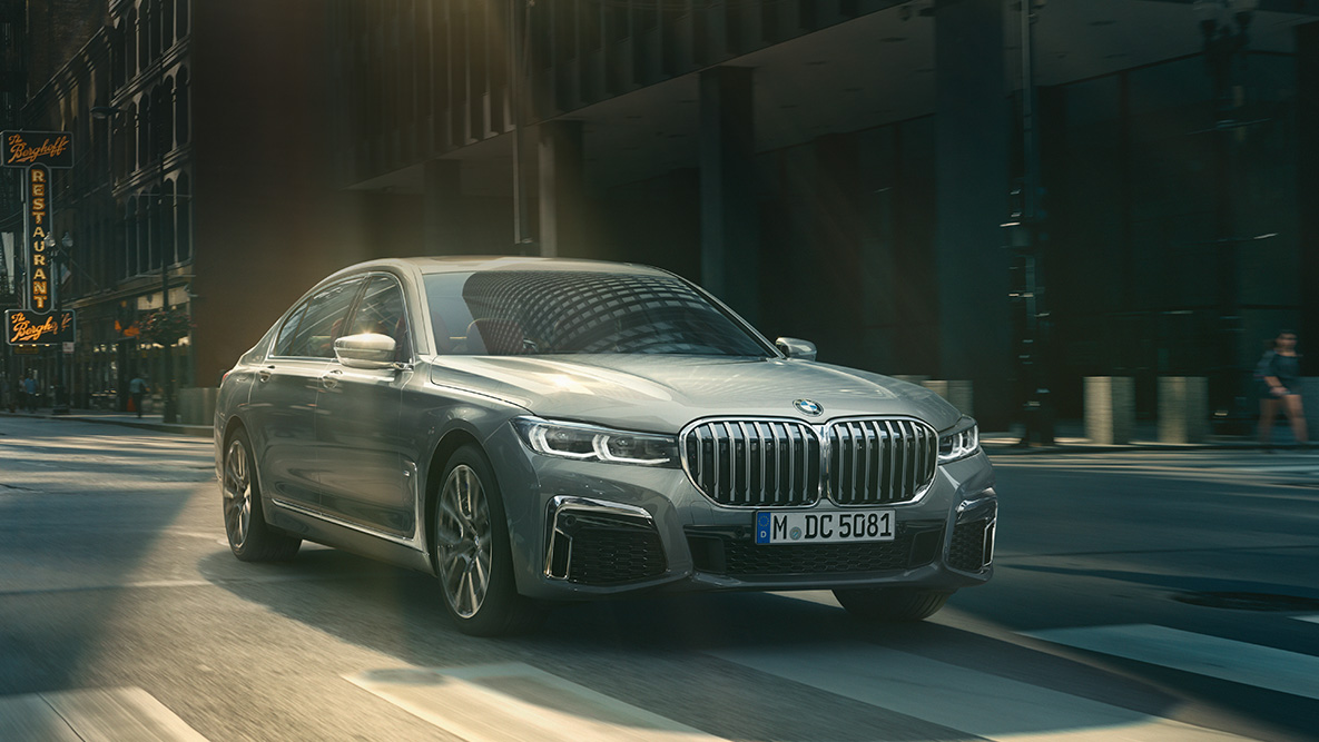 BMW 7-serie Sedan med Driving Assistant Professional Driving Assistant Professional: BMW 7-serie Sedan som kjører foran bylandskap, sett skrått forfra