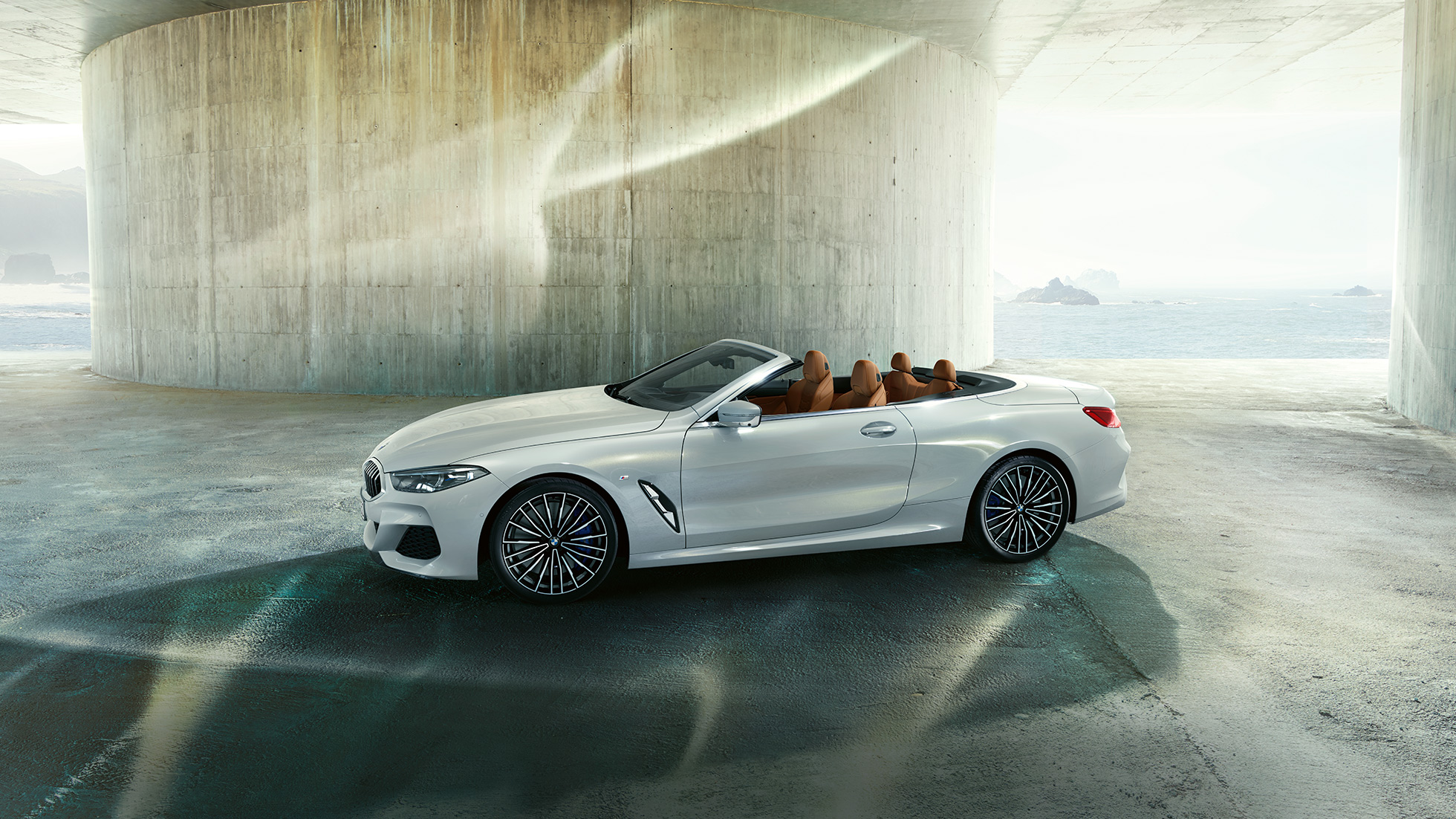 BMW M850i xDrive i mineralhvit metalliclakk med åpen kalesje sett fra siden. BMW M850i xDrive i mineralhvit metalliclakk med åpen kalesje sett fra siden.