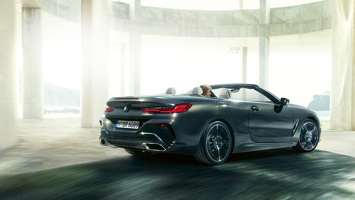 BMW M850i xDrive som kjører med åpen kalesje, sett fra siden. BMW M850i xDrive som kjører med åpen kalesje, sett fra siden.