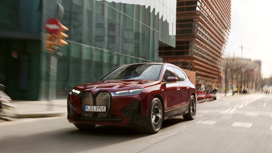 BMW iX i20 elektrisk SUV BMW iX xDrive50 førerassistanse BMW iX i20 2021 elektrisk SUV BMW iX xDrive50 Aventurinrød kjørende i urbane omgivelser