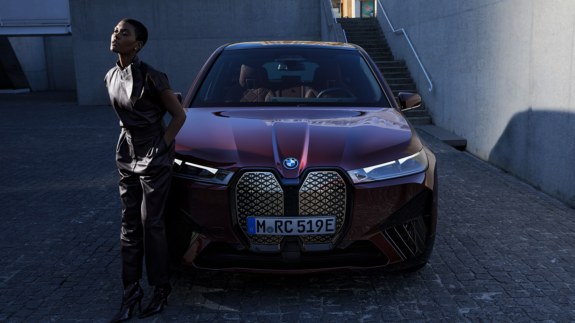 BMW iX sett forfra med modell BMW iX aventurinrød i20 sett forfra med modell