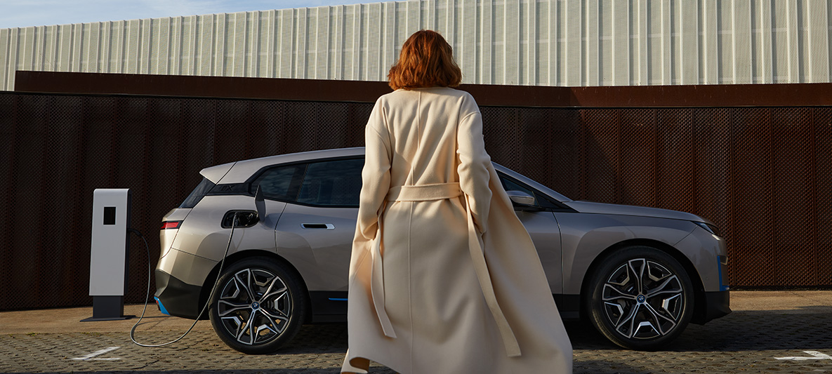 BMW iX sett fra siden stående BMW iX kashmirsølv i20 sett fra siden stående med modell foran