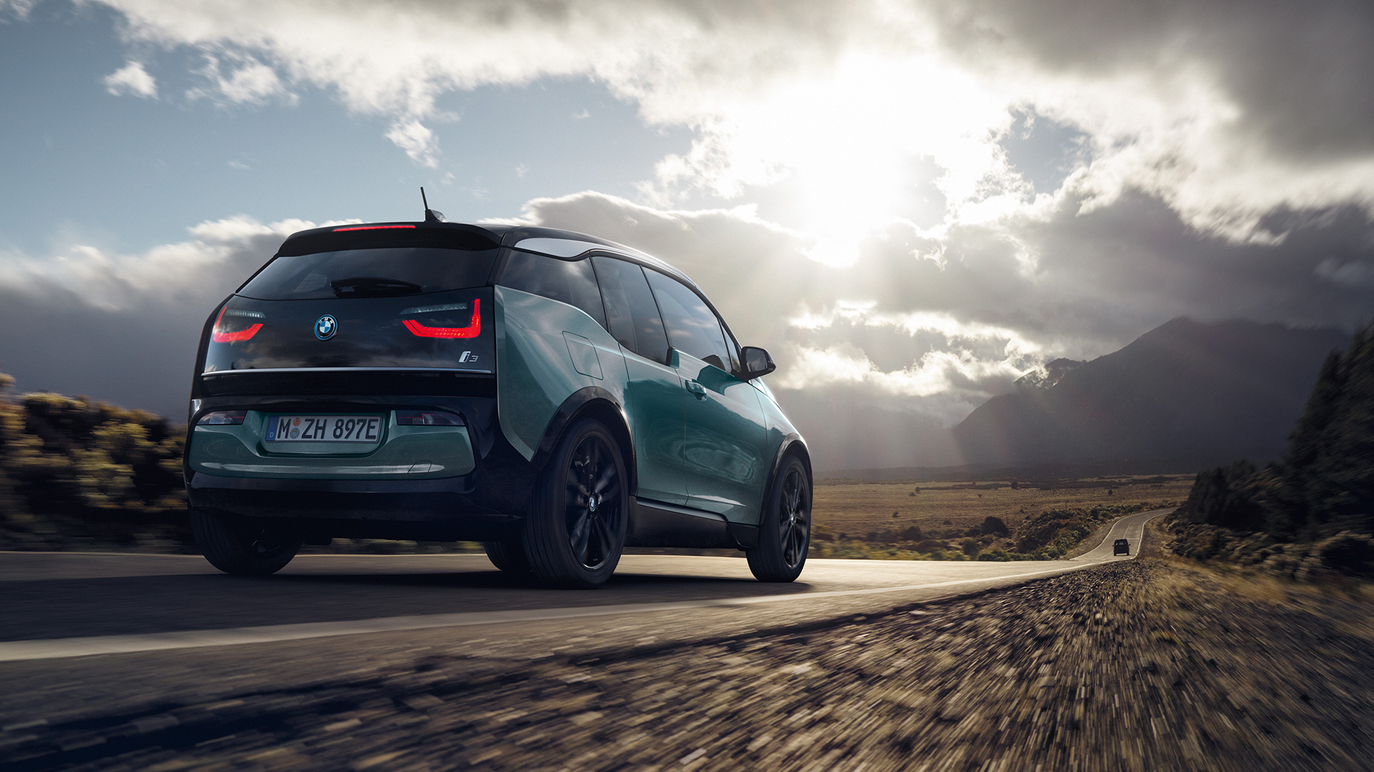 BMW i3 2018 sett skrått bakfra kjørende på landevei BMW i3 I01 2018 Jucarobeige med detaljer i frostgrå metallic sett skrått bakfra kjørende på landevei