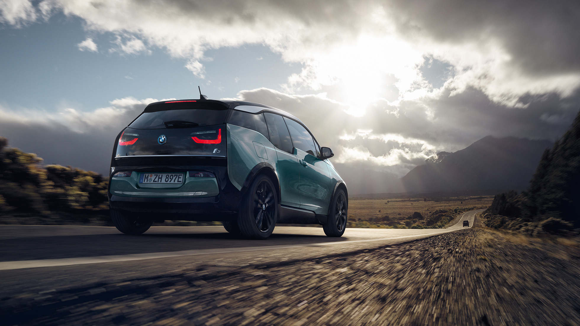 BMW i3 2018 Jucarobeige sett skrått bakfra kjørende på landevei BMW i3 I01 2018 Jucarobeige med detaljer i frostgrå metallic sett skrått bakfra kjørende på landevei