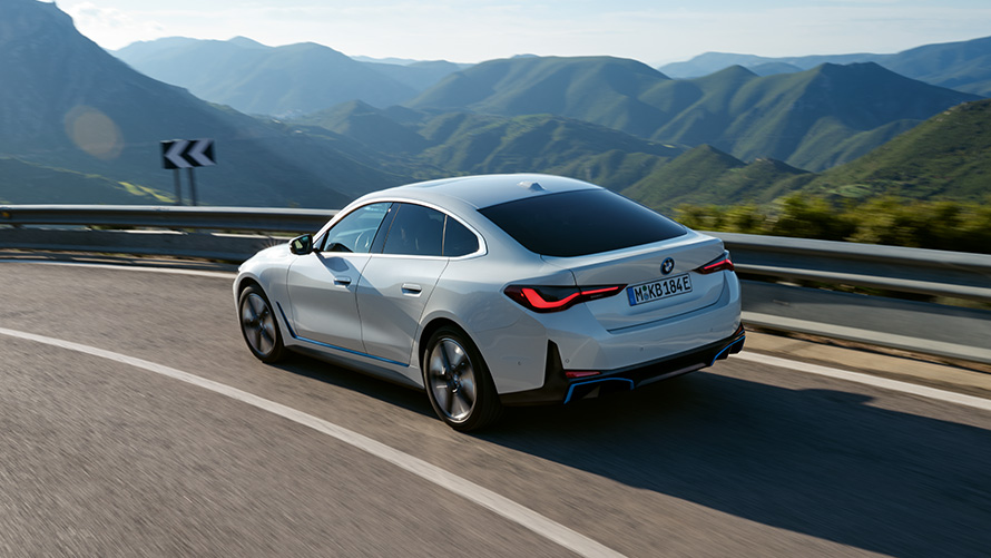 Sett skrått bakfra BMW i4 eDrive40 G26 2021 kjørende BMW i4 eDrive40 G26 2021 Mineralhvit Sett skrått bakfra kjørende