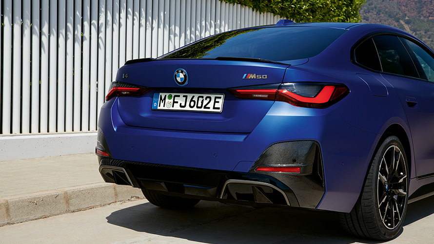 BMW i4 M50 G26 2021 BMW Individual frostet Portimaoblå metallic sett skrått bakfra stående ved hvitt gjerde