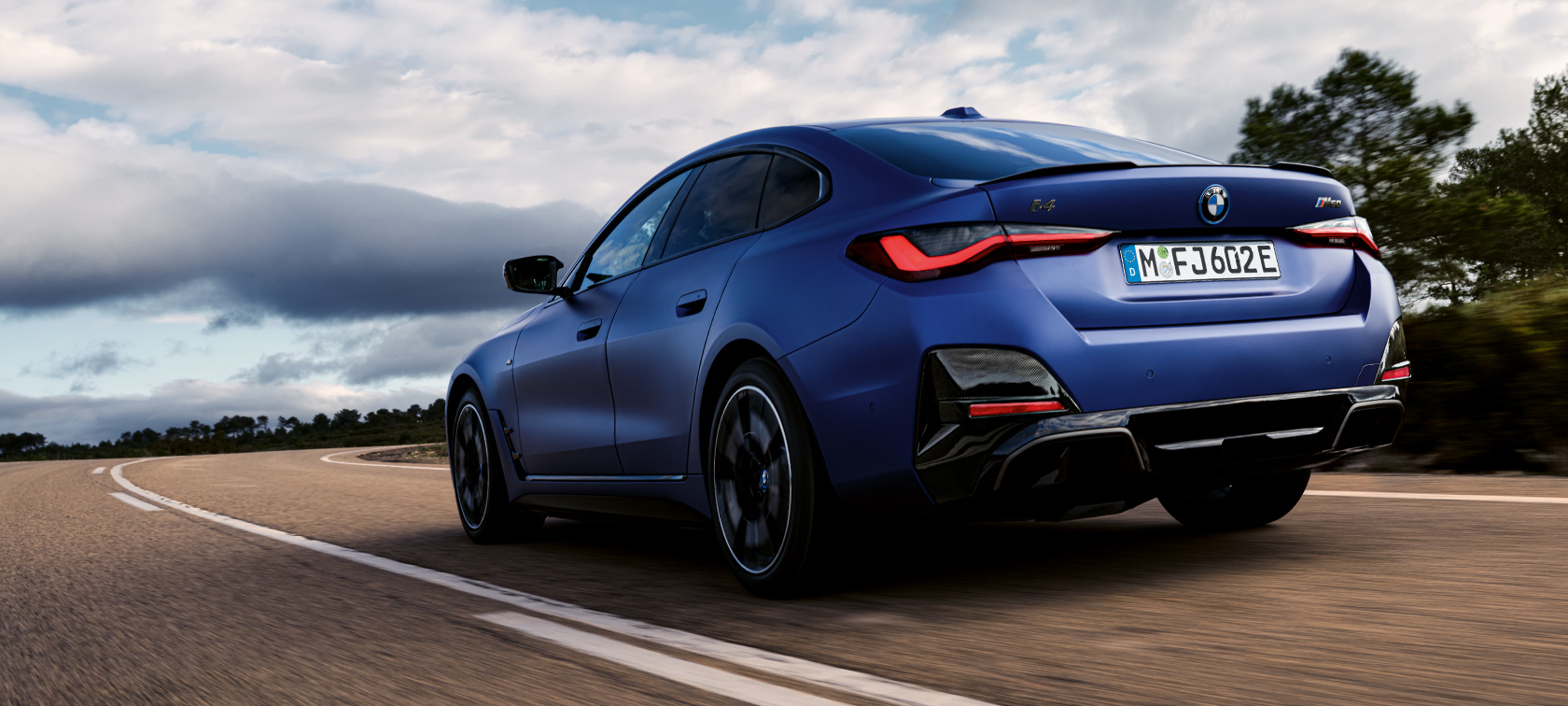 Sett skrått bakfra BMW i4 M50 G26 2021 BMW i4 M50 G26 2021 BMW Individual frostet Portimaoblå metallic sett skrått bakfra kjørende
