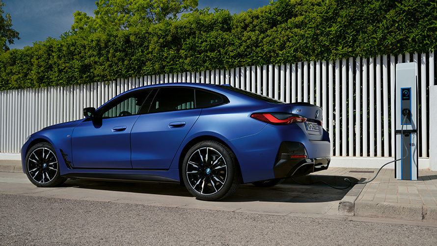 BMW i4 M50 G26 2021 sett fra siden på en offentlig hurtigladestasjon BMW i4 M50 G26 2021 BMW Individual frostet Portimaoblå metallic sett fra siden tilkoblet offentlig hurtigladestasjon