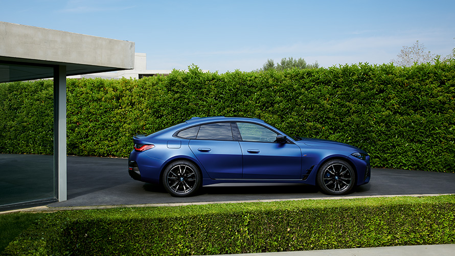 Sett bakfra BMW i4 M50 G26 2021 kjørende på landevei BMW i4 M50 G26 2021 BMW Individual frostet Portimaoblå metallic sett bakfra kjørende på landevei