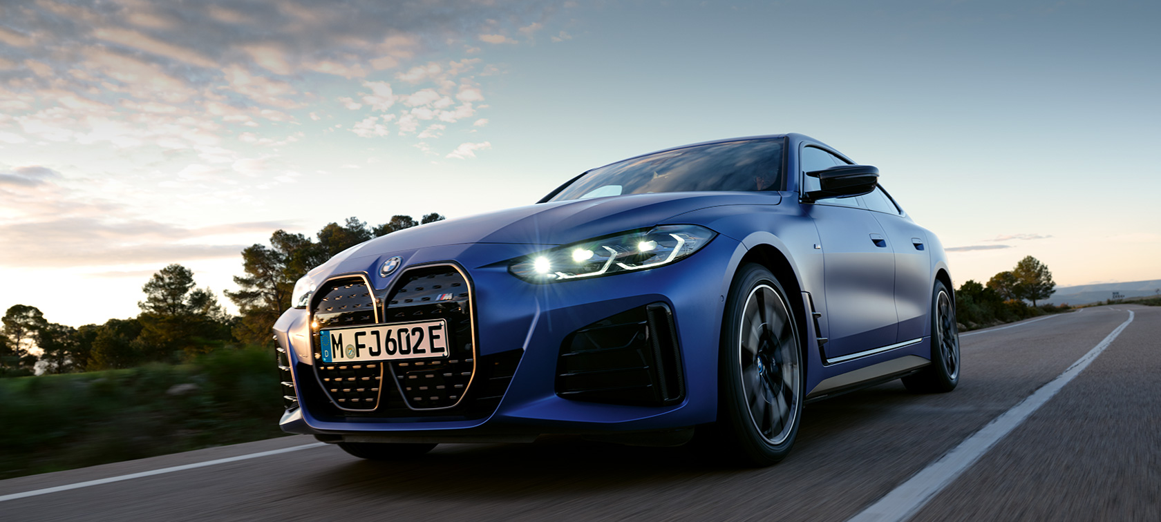 BMW i4 M50 G26 2021 sett fra siden stående foran steinete terreng BMW i4 M50 G26 2021 BMW Individual frostet Portimaoblå metallic sett fra siden stående foran steinete terreng