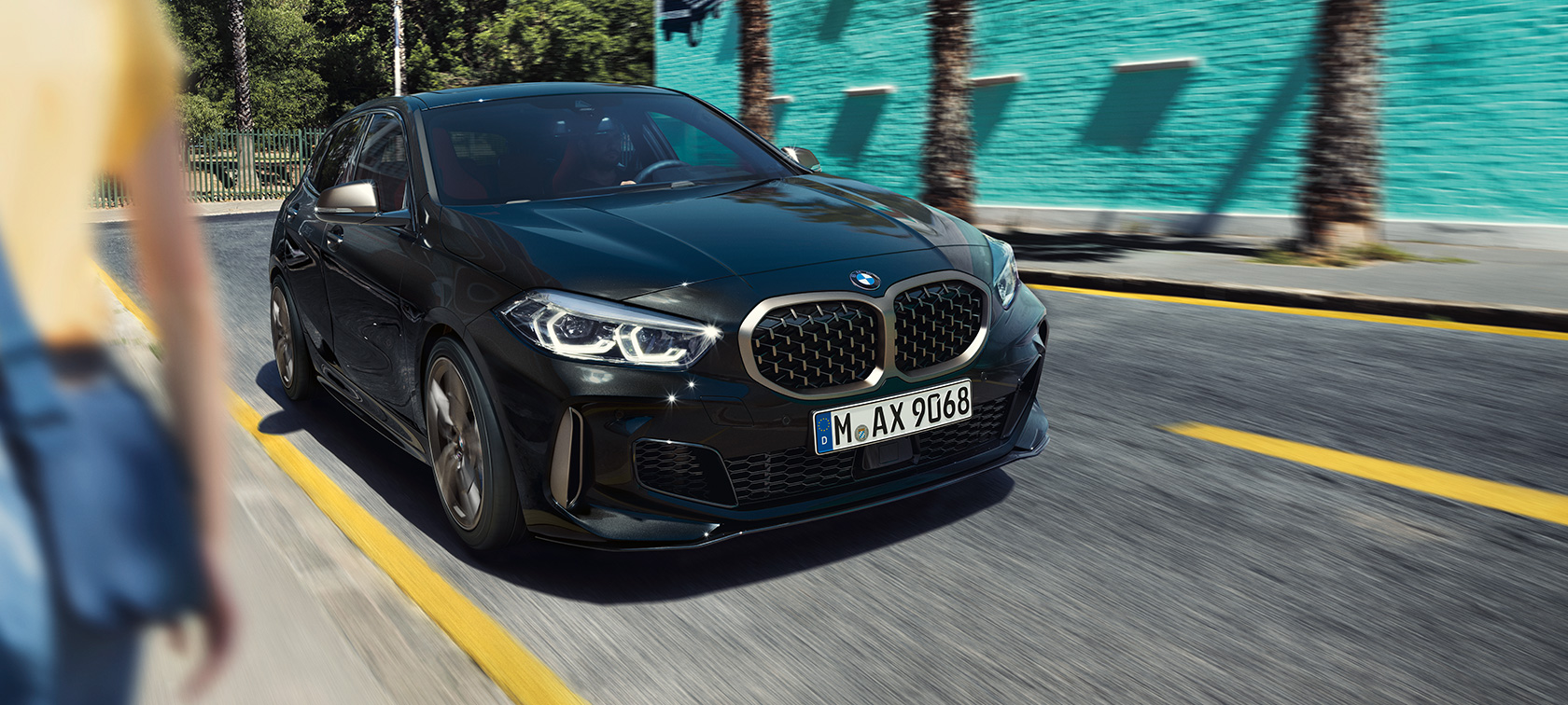 BMW M135i xDrive, sett skrått forfra. BMW M135i xDrive i safirsort metallic, skrått forfra, kjørende.
