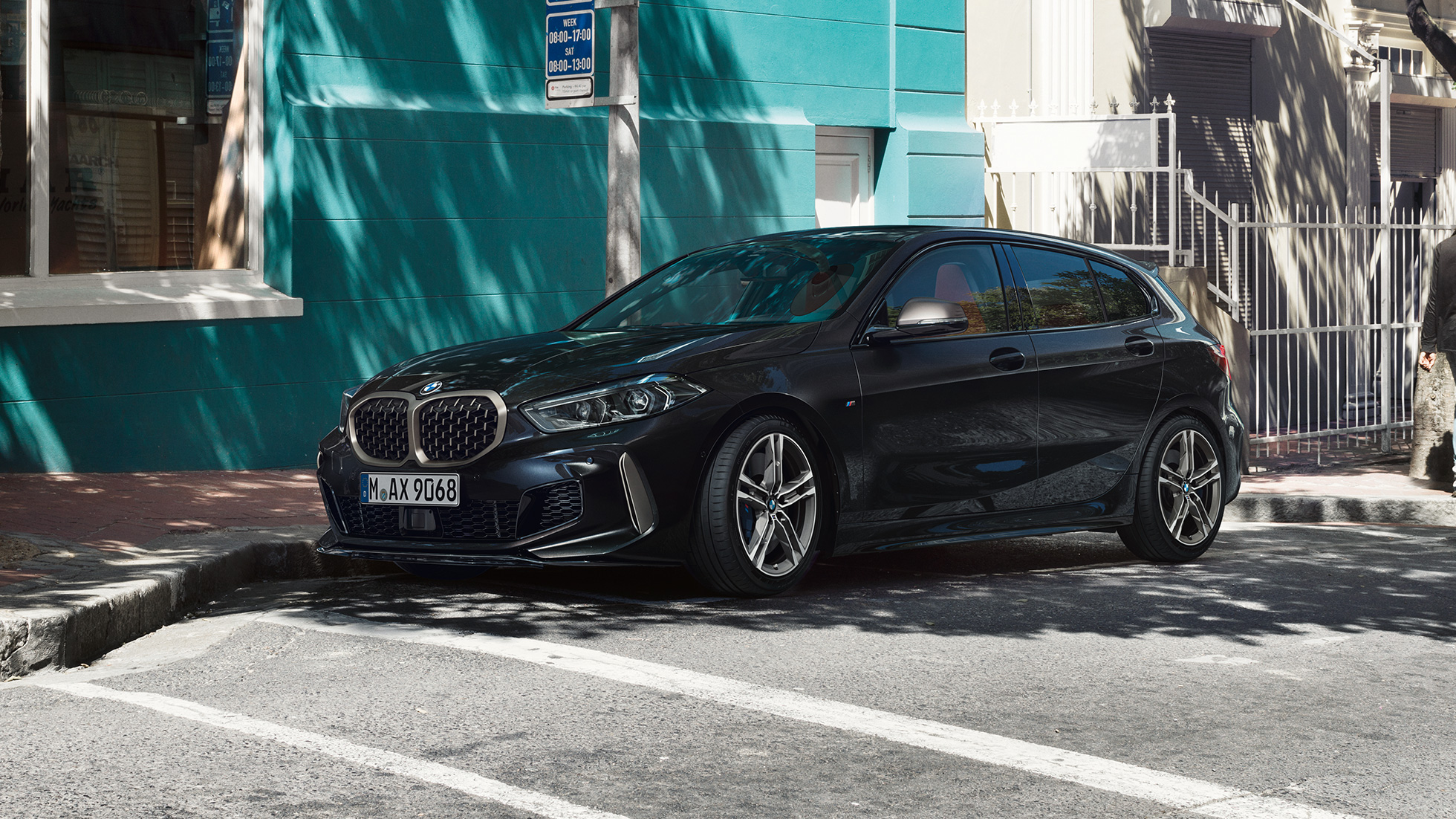 BMW M135i xDrive, skrått fra siden. BMW M135i xDrive i safirsort metallic, skrått fra siden, parkert.