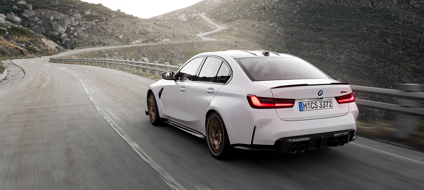 BMW M3 CS G80 sett på skrått bakfra kjørende BMW M3 CS G80 sett på skrått bakfra kjørende på fjellvei
