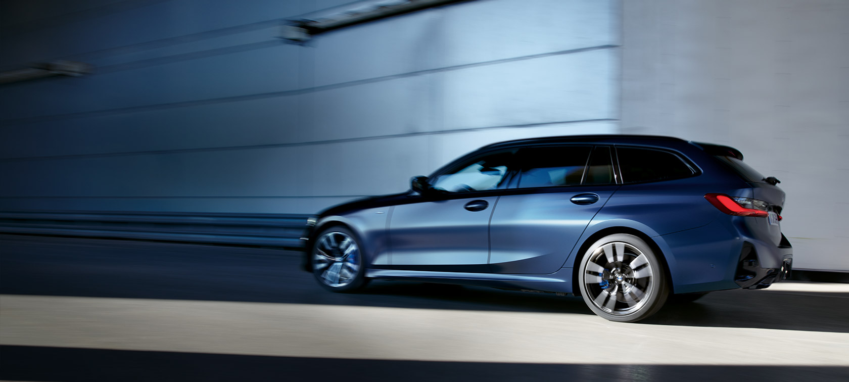 BMW M340i xDrive Touring G21 Frozen Tanzanite blå, sett skrått fra siden kjørende