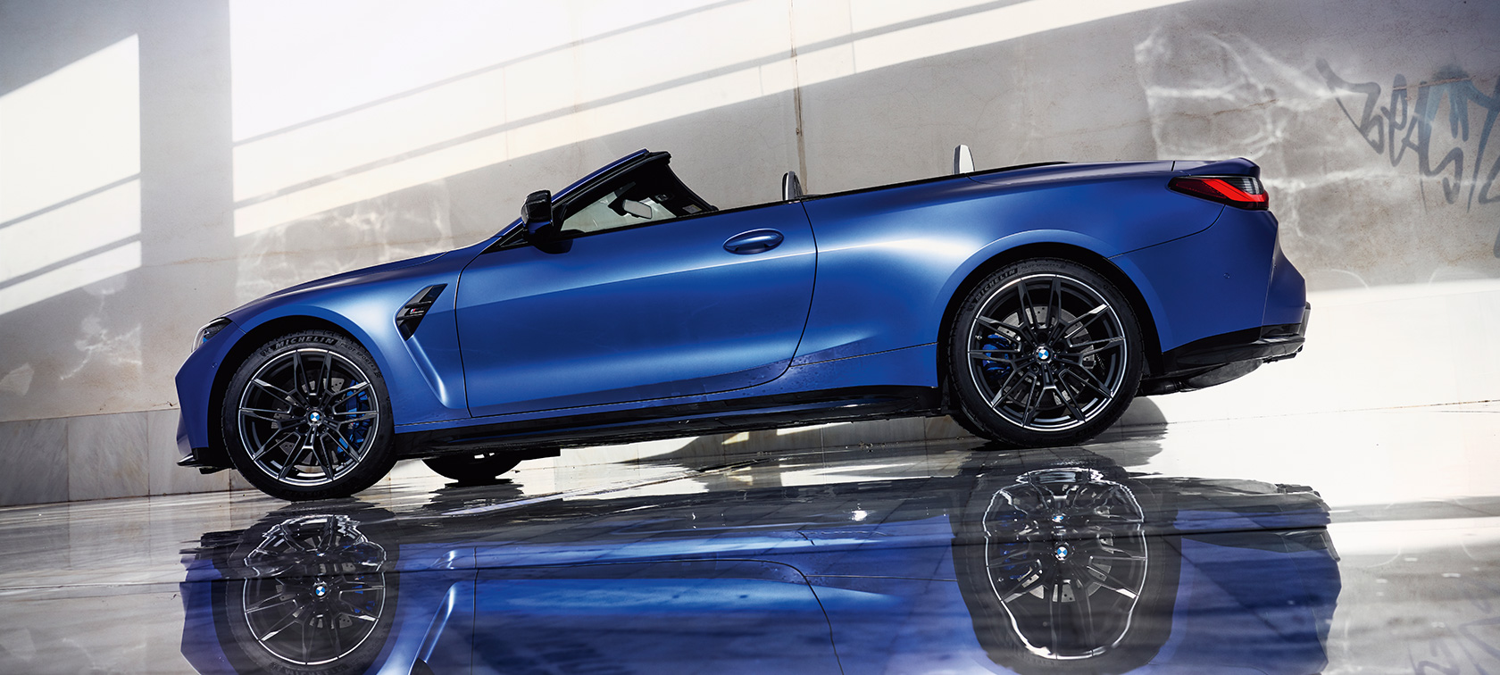 BMW M4 Competition Cabriolet med M xDrive G83 2021 sett skrått forfra kjørende BMW M4 Competition M Cabriolet med M xDrive G83 2021 BMW Individual frostet Portimaoblå metallic sett skrått forfra kjørende
