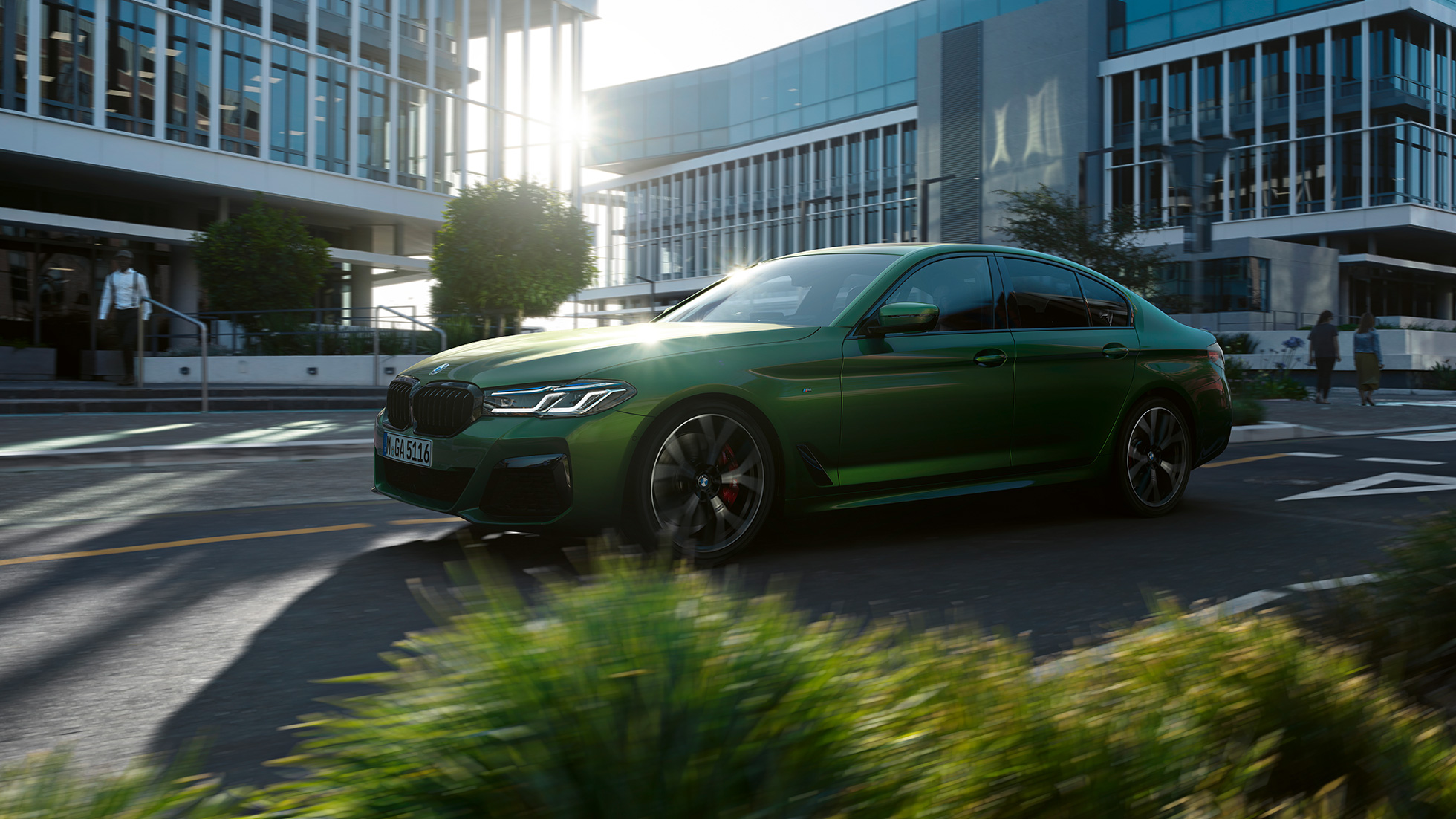 BMW M550i xDrive Sedan G30 LCI Facelift 2020 Sett fra siden kjørende BMW M5 Competition F90 LCI Facelift 2020 BMW Individual Verde Ermes grønn metallic Sett fra siden kjørende i byen