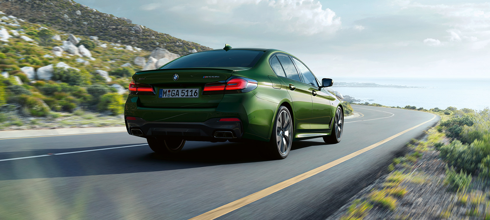 BMW M550i xDrive Sedan G30 LCI Facelift 2020 Sett skrått bakfra kjørende BMW M550i xDrive Sedan G30 LCI Facelift 2020 BMW Individual Verde Ermes grønn metallic sett skrått bakfra kjørende